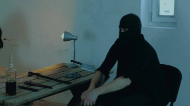 Terk edilmiş bir binada rehine olarak genç bir kadını kaçırırken elinde silah tutan bir erkek terörist. Adam kaçırma konsepti. Yavaş çekim