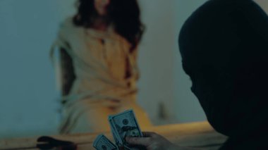 Ağlarken iple bağlanmış korkmuş bir kadın. Suçlu para sayıyor, fidye istiyor. Siyah kar maskeli bir adam kaçırıldı. Fidye. Adam kaçırma, suç, şiddet kavramı. Yavaş çekim