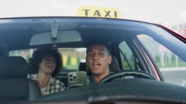 Arka koltukta oturan bayanla konuşan mutlu Afrikalı Amerikalı taksi şoförü. Sarı taksi arabası tabelası. İnsanlar, iş, hizmet kavramı. Yavaş çekim