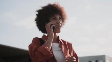 Şehirde taksi beklerken Afro-Amerikalı bir kadın cep telefonuyla konuşuyor. İnsanlar, yaşam tarzı, seyahat konsepti. Yavaş çekim