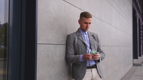 Молодий Чоловік Підраховує Гроші Стоїть Вулиці Біля Стіни Кладе Кишеню — стокове відео