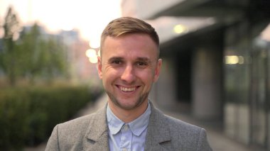 Takım elbiseli genç adam kameraya poz verirken sokakta dikiliyor. İş, iş, insan konsepti. Yavaş çekim