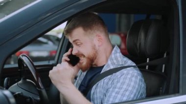 Arabada emniyet kemeri takan başarılı bir genç adam telefonda konuşuyor. Ulaşım, teknoloji, seyahat konsepti. Yavaş çekim