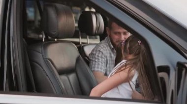 Gülümseyen küçük kız ve babası emniyet kemeri takıp gezintiye çıkmaya hazırlar. Ulaşım, güvenlik, aile kavramı. Yavaş çekim