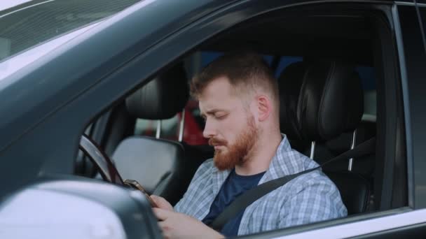 冷静な男性ドライバーは 携帯電話の画面を見てタイピングし 車に座っています トランスポート テクノロジー 旅行コンセプト スローモーション — ストック動画