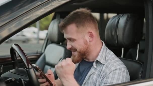 車の運転席に座っている間 若い男がメッセージを読みながら笑った トランスポート テクノロジー 旅行コンセプト スローモーション — ストック動画