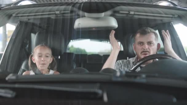 父亲咒骂并驾驶一辆汽车 惊讶地坐在乘客座位上的女儿 家庭观念 慢动作 — 图库视频影像