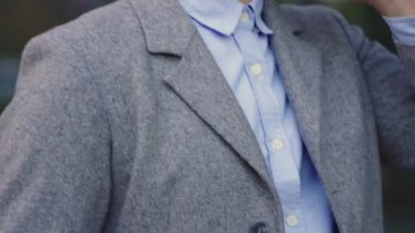 Şık ceketli, cep telefonu kullanan, konuşan, sokakta duran mutlu genç adam. İş, teknoloji kavramı. Gerçek zamanlı.