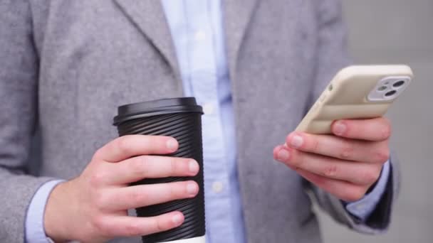 屋外でコーヒーを楽しんでいる間 携帯電話を持ってタイピングする若い男 ビジネス テクノロジーコンセプト リアルタイム — ストック動画