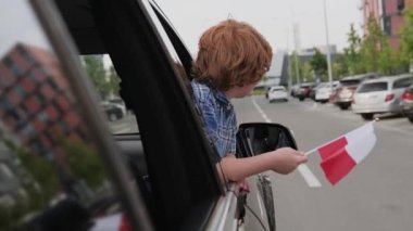 Küçük çocuk Belarus bayrağını gösterirken arabanın camından dışarı bakıyor. Trip, yaşam tarzı konsepti. Yavaş çekim