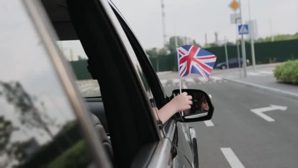 イギリスの国旗を持った子供が市内を車で旅する トリップ ライフスタイルコンセプト スローモーション — ストック動画