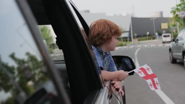 Mały Chłopiec Wyglądający Przez Okno Samochodu Pokazujący Flagę Georgii Podróż — Wideo stockowe