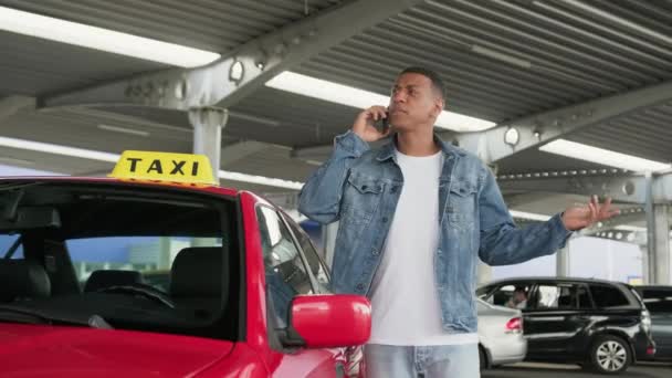 アフリカ系アメリカ人ドライバーが外のタクシー車の近くに立っている間に電話で話している サービスカーのコンセプト スローモーション — ストック動画