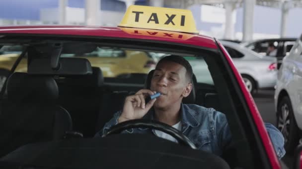 アフリカ系アメリカ人のタクシー運転手が電子タバコを吸っている サービスカー 医療コンセプト スローモーション — ストック動画