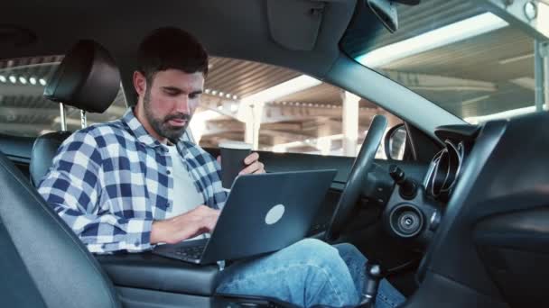 一边喝咖啡一边用笔记本电脑微笑的家伙 坐在车里 生活方式概念 慢动作 — 图库视频影像