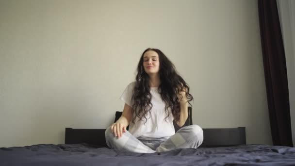 Dama Sonriente Pijama Tocándose Pelo Rizado Mientras Está Sentada Cama — Vídeos de Stock