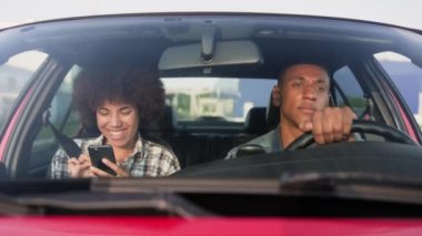 Erkek sürücünün dikkatini dağıtırken cep telefonu kullanan ve gülen mutlu kadın. Yaşam tarzı, ilişki, ulaşım, insanlar, seyahat kavramı. Yavaş çekim