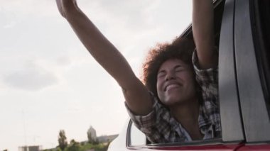 Mutlu Afrikalı Amerikalı kadın pencereden dışarı bakarken arabayla seyahat etmekten zevk alıyor. Ulaşım, seyahat, insanlar, yaşam tarzı konsepti. Yavaş çekim