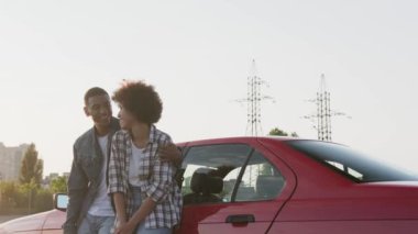 Afrika kökenli Amerikalı çift dışarıda arabanın yanında dikilirken birbirlerine sarılıyorlar. Ulaşım, seyahat, ilişki, insan konsepti. Yavaş çekim