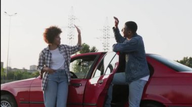 Afrika kökenli Amerikalı çift arabalarının yanında durup beşlik çakıyor ve gülümsüyor. Ulaşım, seyahat, ilişki, insan konsepti. Yavaş çekim
