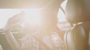 Akıllı telefon kullanarak gülümseyen Afrikalı Amerikalı kadın ve selfie çekmek, taksinin arka koltuğunda el sallamak. İnsanlar, yaşam tarzı, teknoloji konsepti. Yavaş çekim