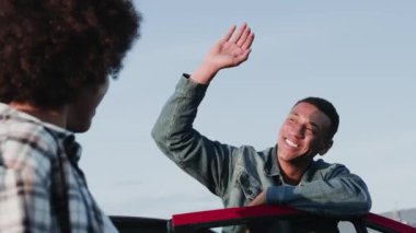 Gülümseyen Afrikalı Amerikalı adam kadınlara beşlik çakıyor, dışarıda dikiliyor. Ulaşım, seyahat, ilişki, insan konsepti. Yavaş çekim