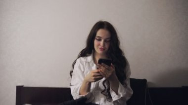 Evdeki yatak odasındaki cep telefonunda yazarken esneyen güzel bir kadın. Ağır çekim. Yaşam tarzı kavramı