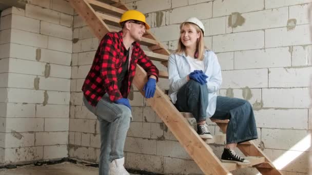 Fröhliche Bauarbeiterin Sitzt Auf Einer Treppe Rohbau Und Plaudert Mit — Stockvideo