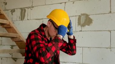 Sakin müteahhit tuğla duvara yaslanmış koruyucu miğfer ve gözlük takıyor. Yavaş çekim