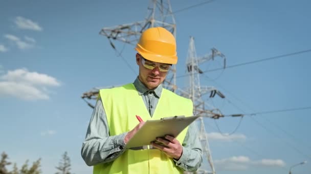 Smiling Power Line Inspector Making Notes Clipboard While Posing Camera — Stock Video
