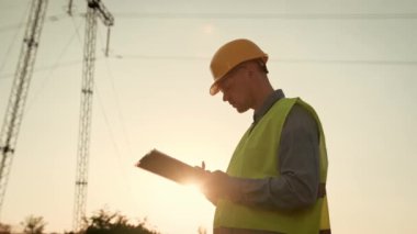 Panoya kalem ile odaklanmış enerji denetleyicisi yazımı ve elektrik direğinin yanında dururken mesafeye bakmak. Yavaş çekim