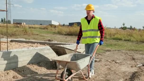 Bauarbeiter Schutzhelm Und Handschuhen Schieben Schubkarre Über Den Boden Entlang — Stockvideo