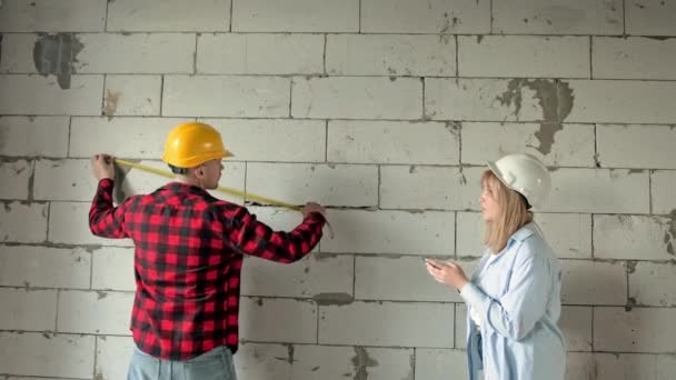 Bauarbeiter Messen Länge Und Breite Der Wände Während Sein Kollege — Stockvideo