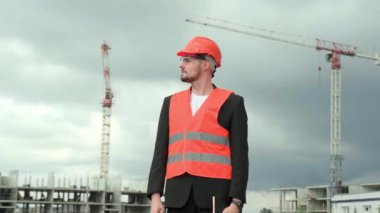 Korumalı miğfer, yelek ve gözlük takan profesyonel müteahhit portresi siteye bakıyor. Yavaş çekim