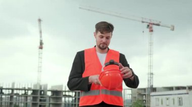 Korumalı yelek giyen profesyonel müteahhit portresi inşaat alanında çalışmak için sıkı bir şapka takıyor. Yavaş çekim