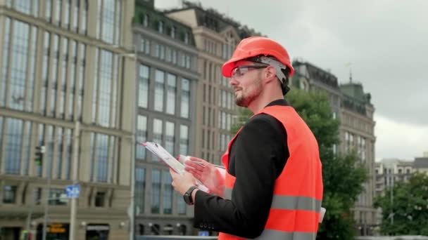 Chaleco Masculino Casco Protector Gafas Con Planos Mirando Edificios Tomando — Vídeos de Stock