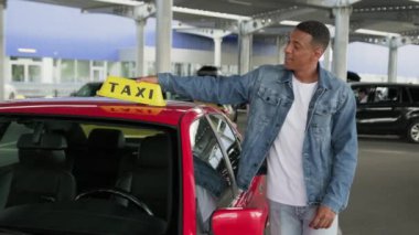 Arabasının yanında poz veren Afro-Amerikan taksi şoförü, iyi bir hareket gösteriyor. Servis arabası konsepti. Yavaş çekim