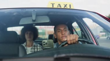 Afrikalı Amerikalı taksi şoförü bir kadınla arka koltukta araba kullanıyor. Sarı taksi arabası tabelası. İnsanlar, iş, hizmet kavramı. Yavaş çekim