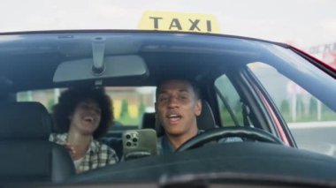 Arka koltukta oturan bayanla konuşan mutlu Afrikalı Amerikalı taksi şoförü. Sarı taksi arabası tabelası. İnsanlar, iş, hizmet kavramı. Yavaş çekim