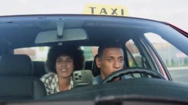 Arabada arka koltukta oturan genç bayan taksi şoförüyle konuşuyor. Sarı taksi arabası tabelası. İnsanlar, iş, hizmet kavramı. Yavaş çekim