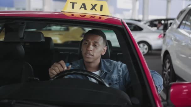 アフリカ系アメリカ人のタクシー運転手が電子タバコを吸っている間に車に座っている 黄色いタクシー車の屋根サイン 健康の概念 スローモーション — ストック動画