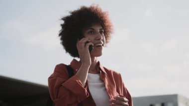 Şehirde taksi beklerken Afro-Amerikalı bir kadın cep telefonuyla konuşuyor. İnsanlar, yaşam tarzı, seyahat konsepti. Yavaş çekim
