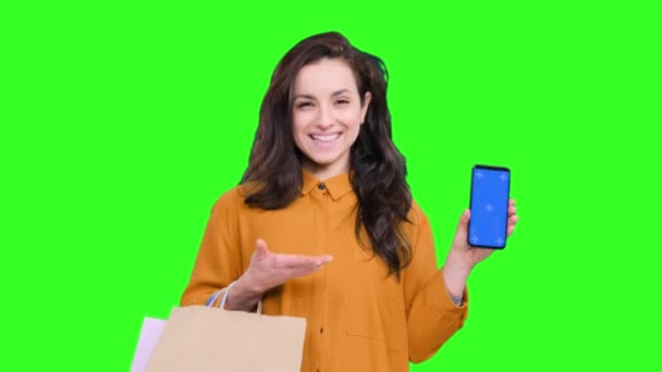 快乐的女人背着五颜六色的购物袋 手握聪明的磨坊 屏幕上的复制空间与绿色隔离的背景 黑色星期五 销售概念 — 图库视频影像