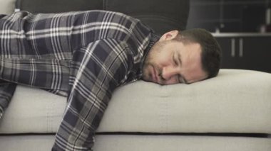Kafkasyalı sakallı bir adam, evdeki kanepede uyurken gündelik bir şekilde yatıyor. Dinlenme, uyku zamanı ve insanlar konsepti. Yavaş çekim