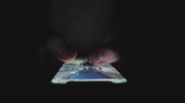 Karanlıkta parmaklarıyla ekrana dokunurken cep telefonu kullanan bir adam. Kapatın. Teknoloji, internet, online, mobil uygulama kavramı. Yavaş çekim