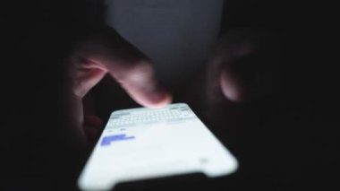 Cep telefonu tutan ve karanlıkta poz veren erkek eller. Kapatın. Teknoloji, internet, online, mobil uygulama kavramı. Yavaş çekim