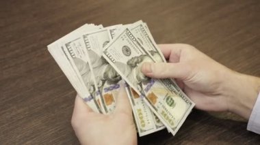 İş adamı elleri masada oturmuş, 100 dolarlık banknotları sayıyor. Üst Manzara. Kapatın. İş, ekonomi konsepti. Yavaş çekim
