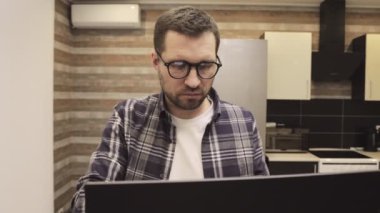 Sıradan ve gözlüklü beyaz sakallı bir adam laptop ekranına bakıyor, daktilo ediyor, çalışıyor. Çevrimiçi çalışma, iş ve teknoloji konsepti. Yavaş çekim