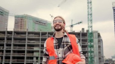 Memnuniyet alan yöneticisi sabit şapka tutarken yarım kalmış çok katlı evin yanında başparmak kaldırıyor. Yavaş çekim