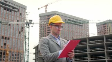 Foreman koruyucu miğferini takmış, panoyu tutuyor ve not alıyor. Yavaş çekim videosu